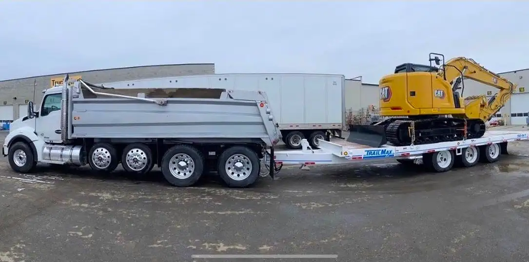 C. Watts Trucking dump truck and lowboy trailer hauling a CAT excavator